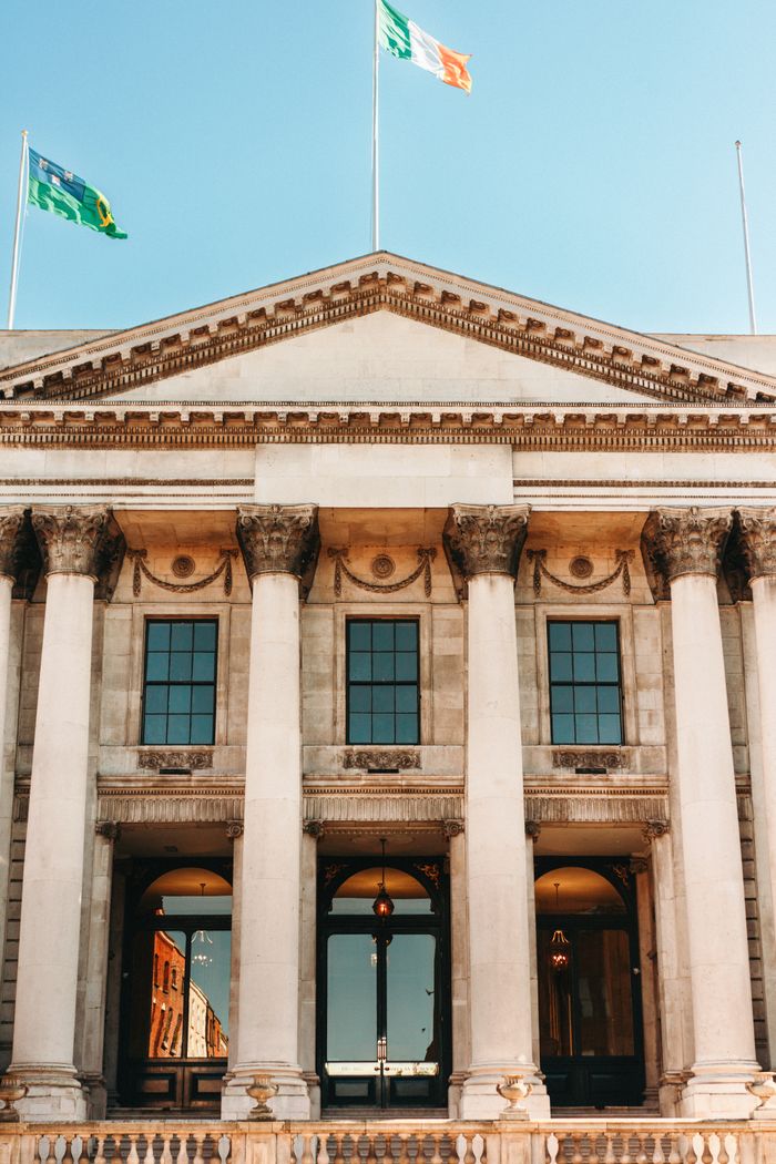 Front view of Dublin City Hall featuring historical architecture with flags flying against a clear sky.